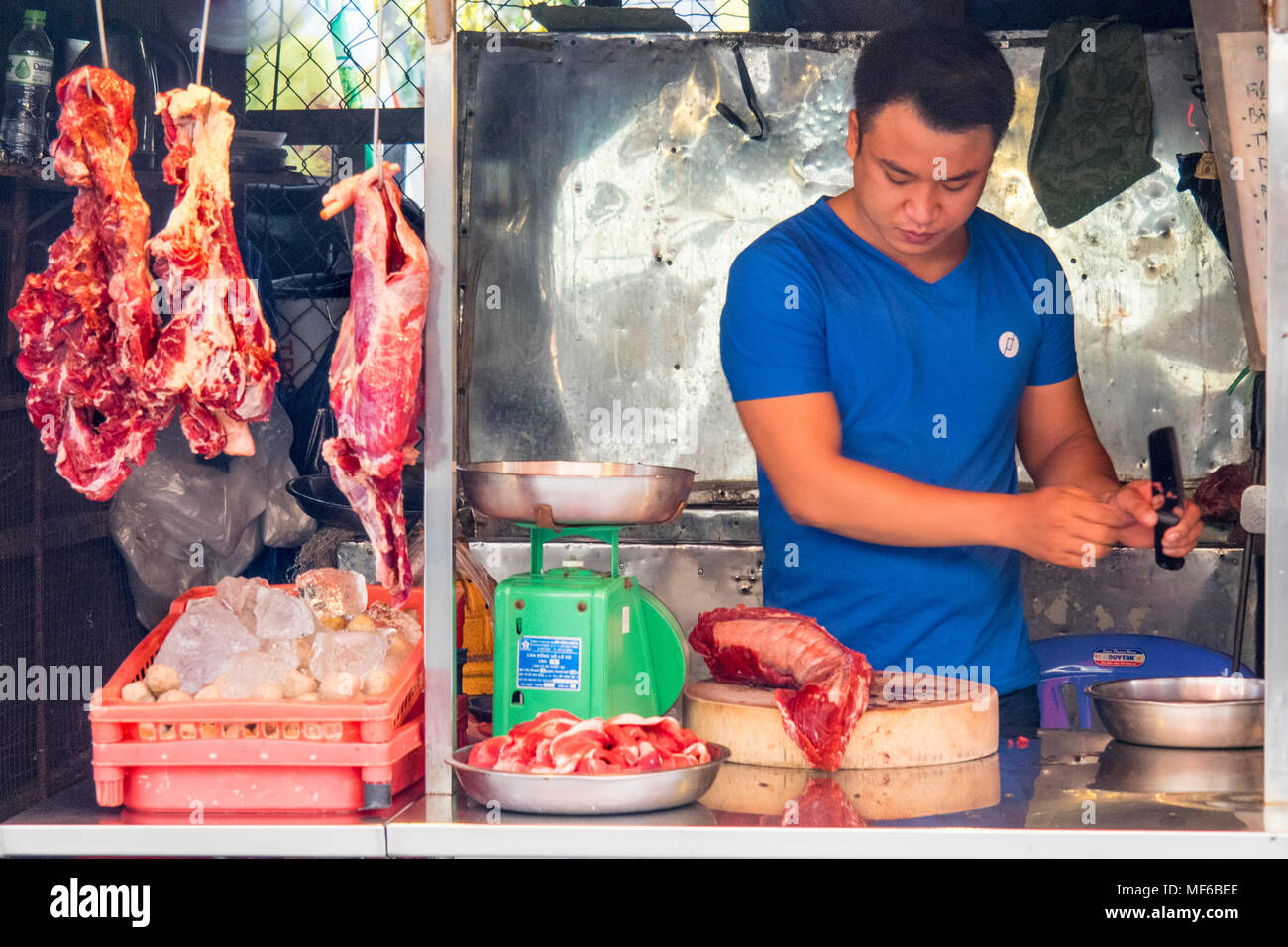 Ein männlicher Metzger Zubereitung von Fleisch in eine Metzgerei in der Tonne stall Dam Straßenmärkte, Ho Chi Minh City, Vietnam. Stockfoto