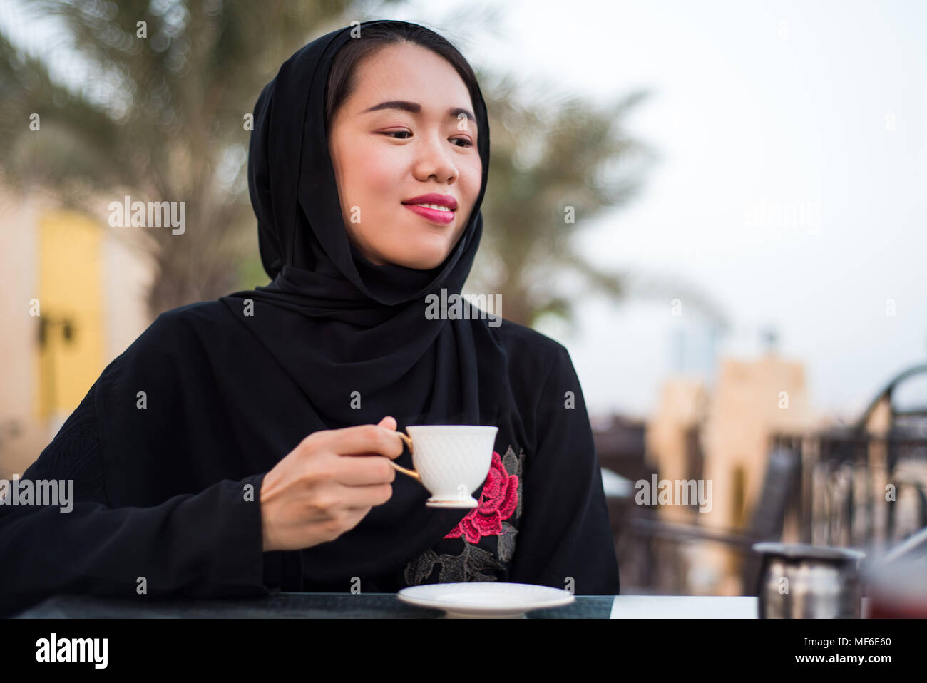 Muslimische Frau mit einer Tasse Kaffee in einer Bar im Freien Stockfoto
