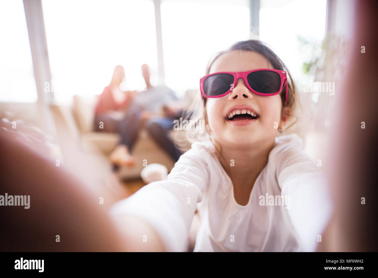 Ein kleines Mädchen mit unkenntlich Eltern unter selfie zu Hause. Stockfoto