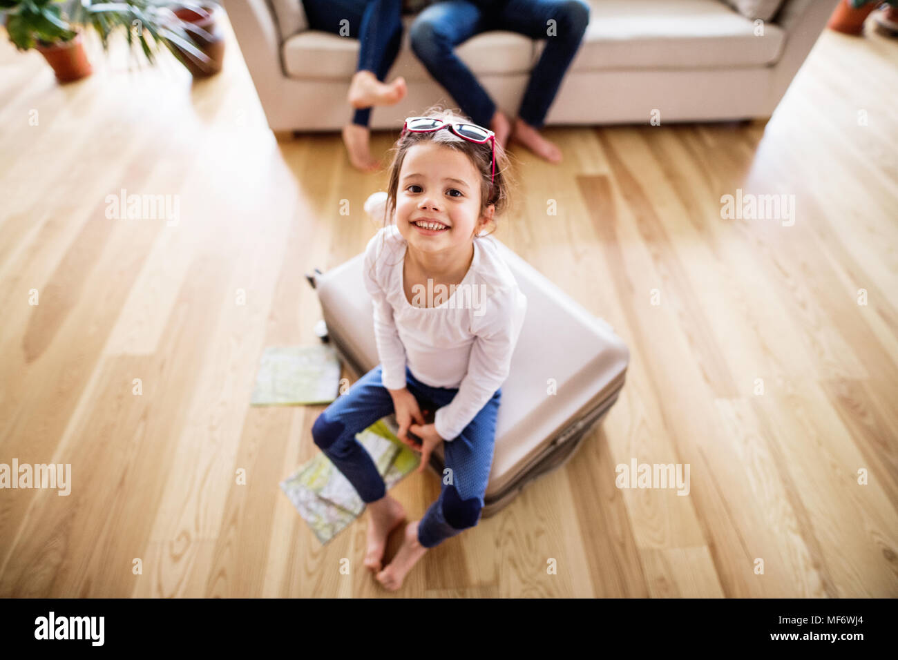 Ein kleines Mädchen mit unkenntlich Eltern Verpackung für einen Urlaub. Stockfoto
