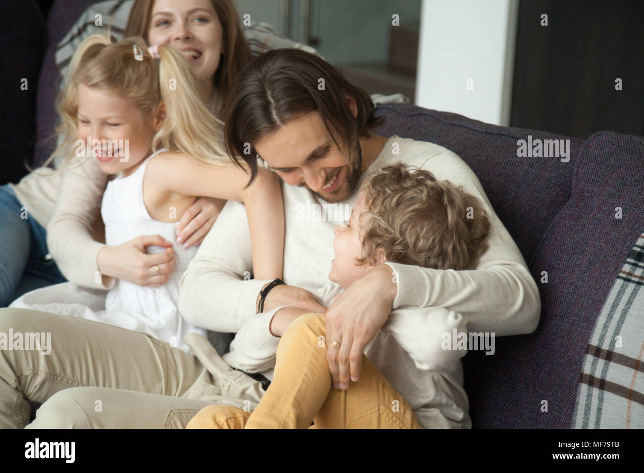 Glückliche Eltern und Kinder lachen Spaß kitzeln auf dem Sofa Stockfoto