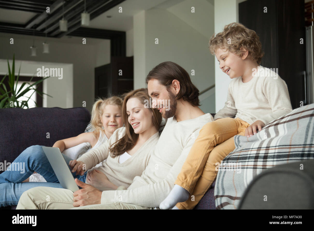 Glückliche Familie mit Kindern mit Laptop auf der Couch zu Hause Stockfoto
