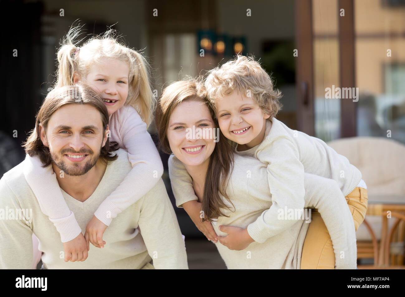 Glückliche Eltern huckepack Kinder auf Haus Terrasse auf der Suche kam Stockfoto