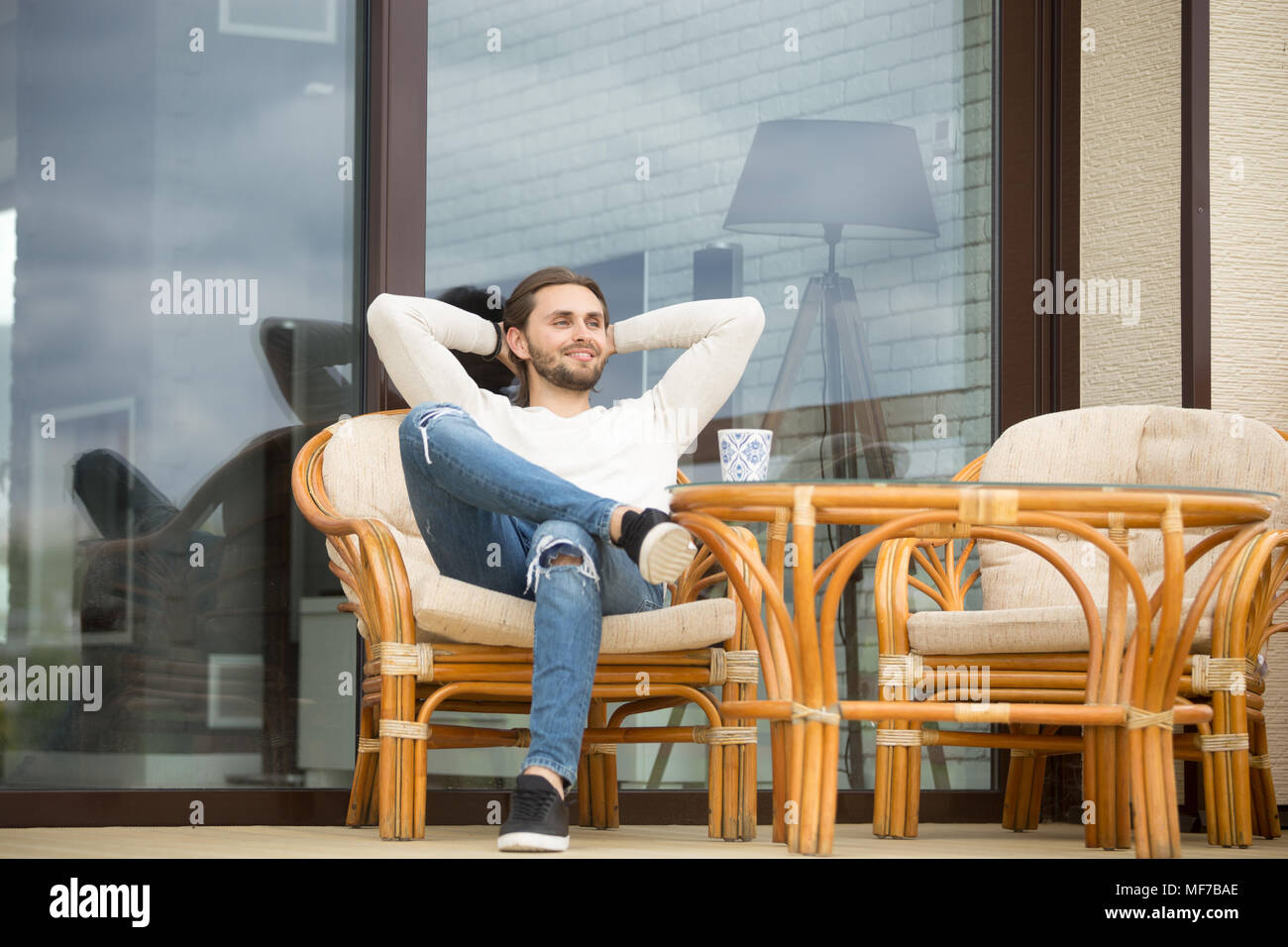 Lächelnd Mann entspannt genießen angenehmen Morgen sitzen auf der Terrasse Stockfoto