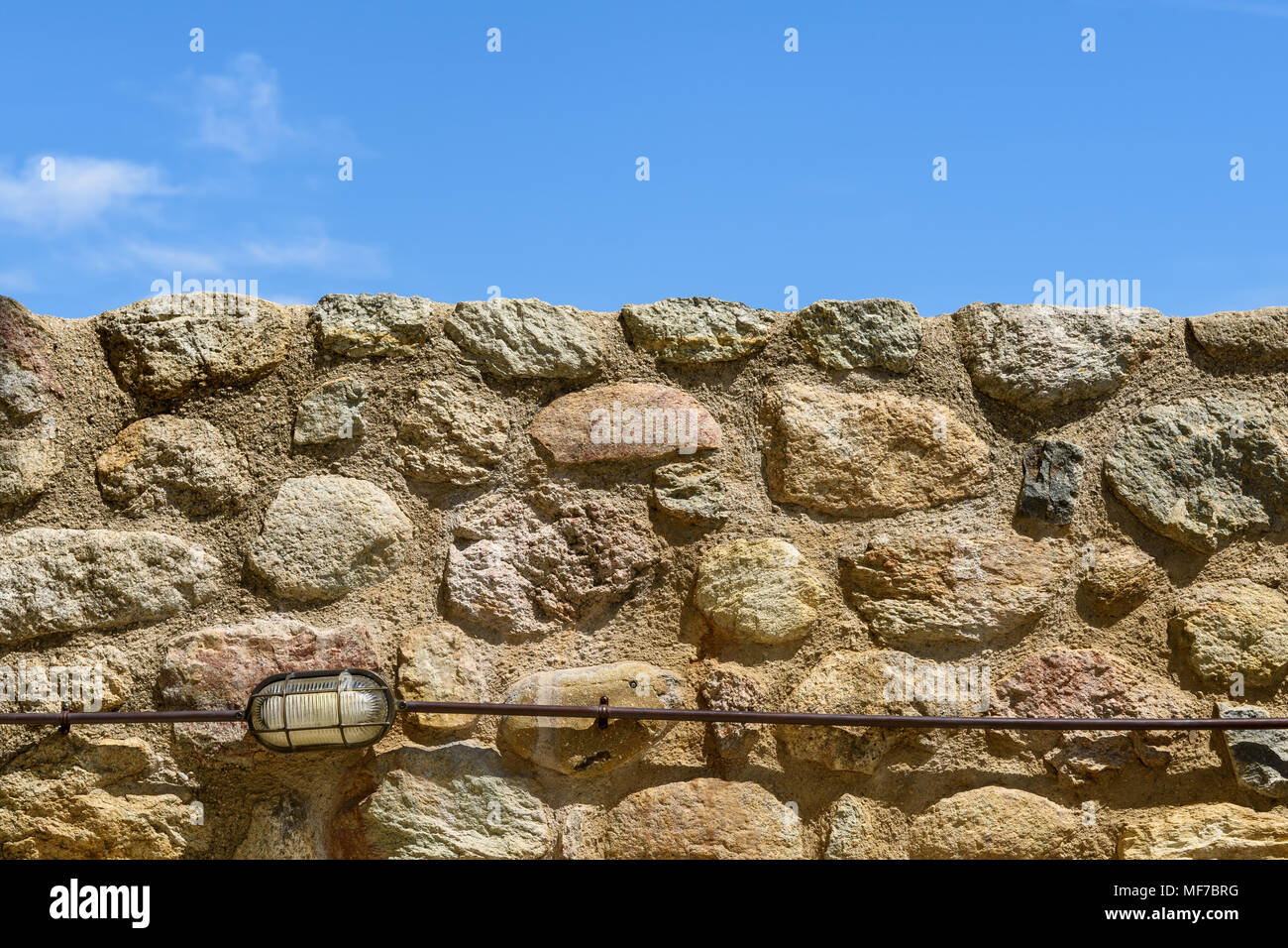 Einfache Hintergrund mit Wand aus verschieden große Steine gegen wolkenlosen Himmel und kleinen outdoor Lampe an der Unterseite Stockfoto