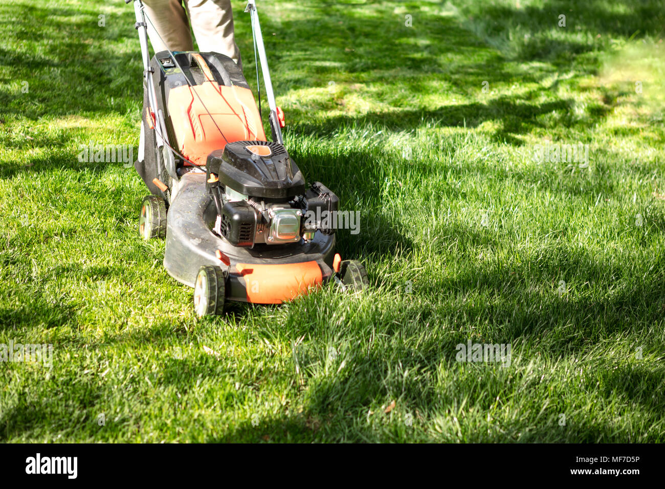Orange Rasenmäher Schneiden von Gras. Gartenarbeit Konzept Hintergrund Stockfoto