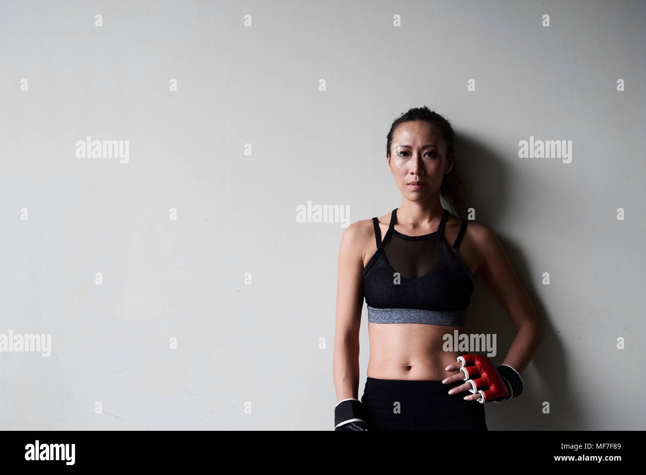 Portrait von zuversichtlich weiblichen Boxer gegen graue Wand Stockfoto