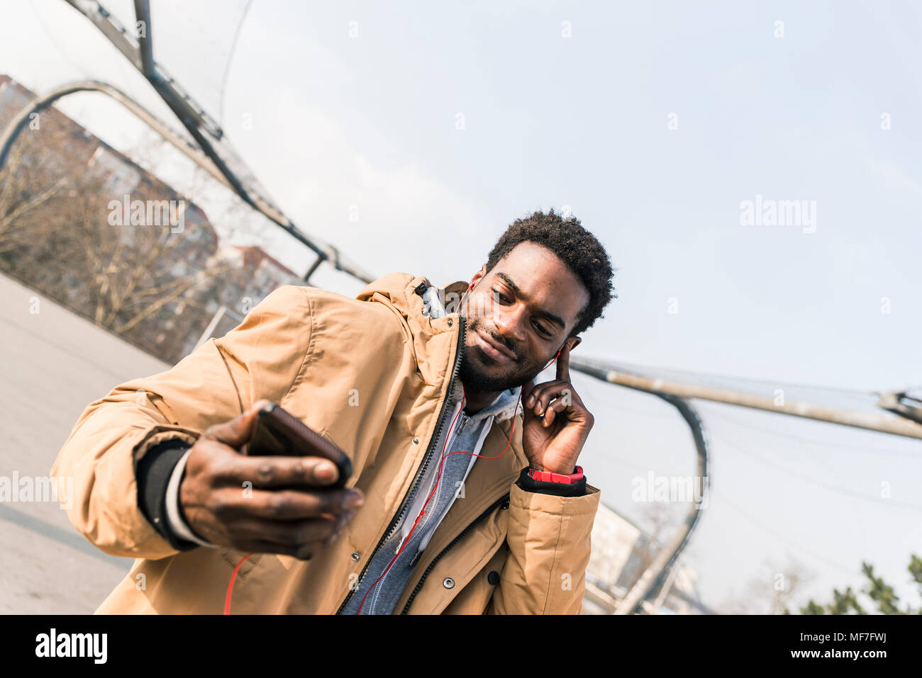 Lächelnden jungen Mann mit Smartphone und Ohrhörer im Freien Stockfoto