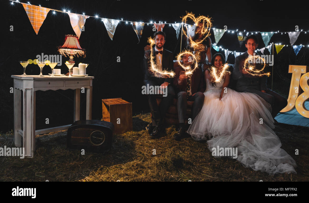 Hochzeitspaar und Freunde machen das Wort 'Liebe' mit Wunderkerzen auf einem Night Party im Freien Stockfoto