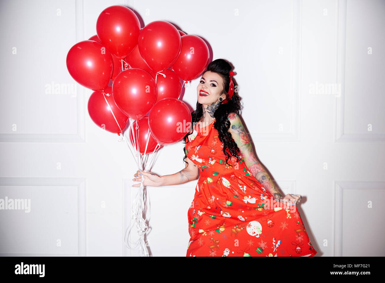 Portrait von tätowierten Frau mit Strauß roter Luftballons Stockfoto
