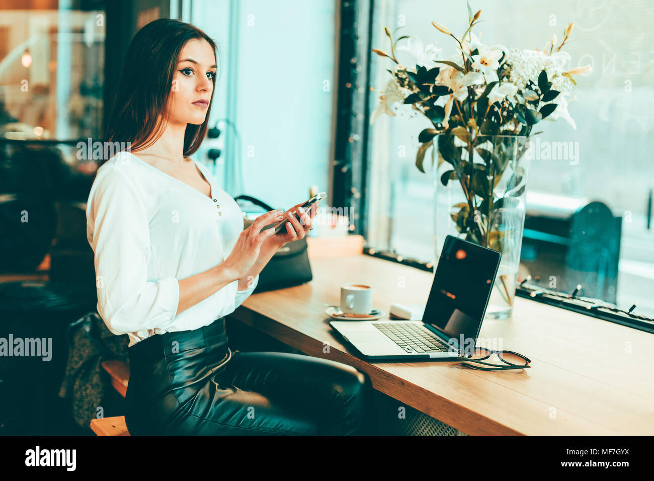 Nachdenkliche junge geschäftsfrau mit Smartphone in einem Coffee Shop Stockfoto