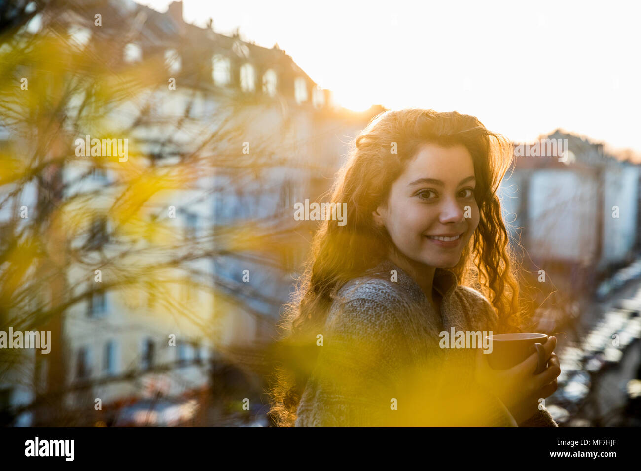 Portrait von Lachen Jugendmädchen mit Kaffeetasse auf dem Balkon in der Dämmerung Stockfoto