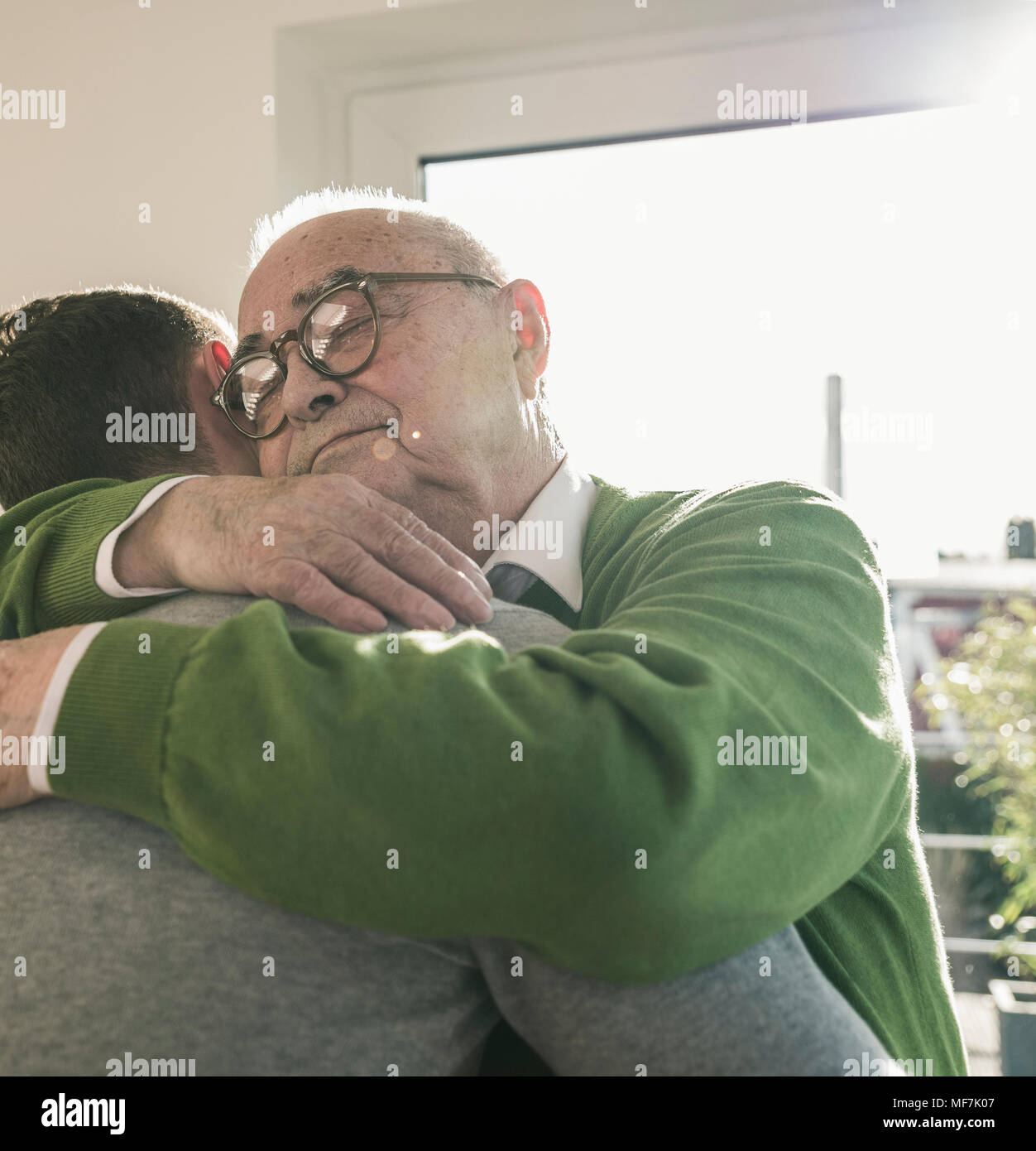 Älterer Mann umarmt jungen Mann Stockfoto
