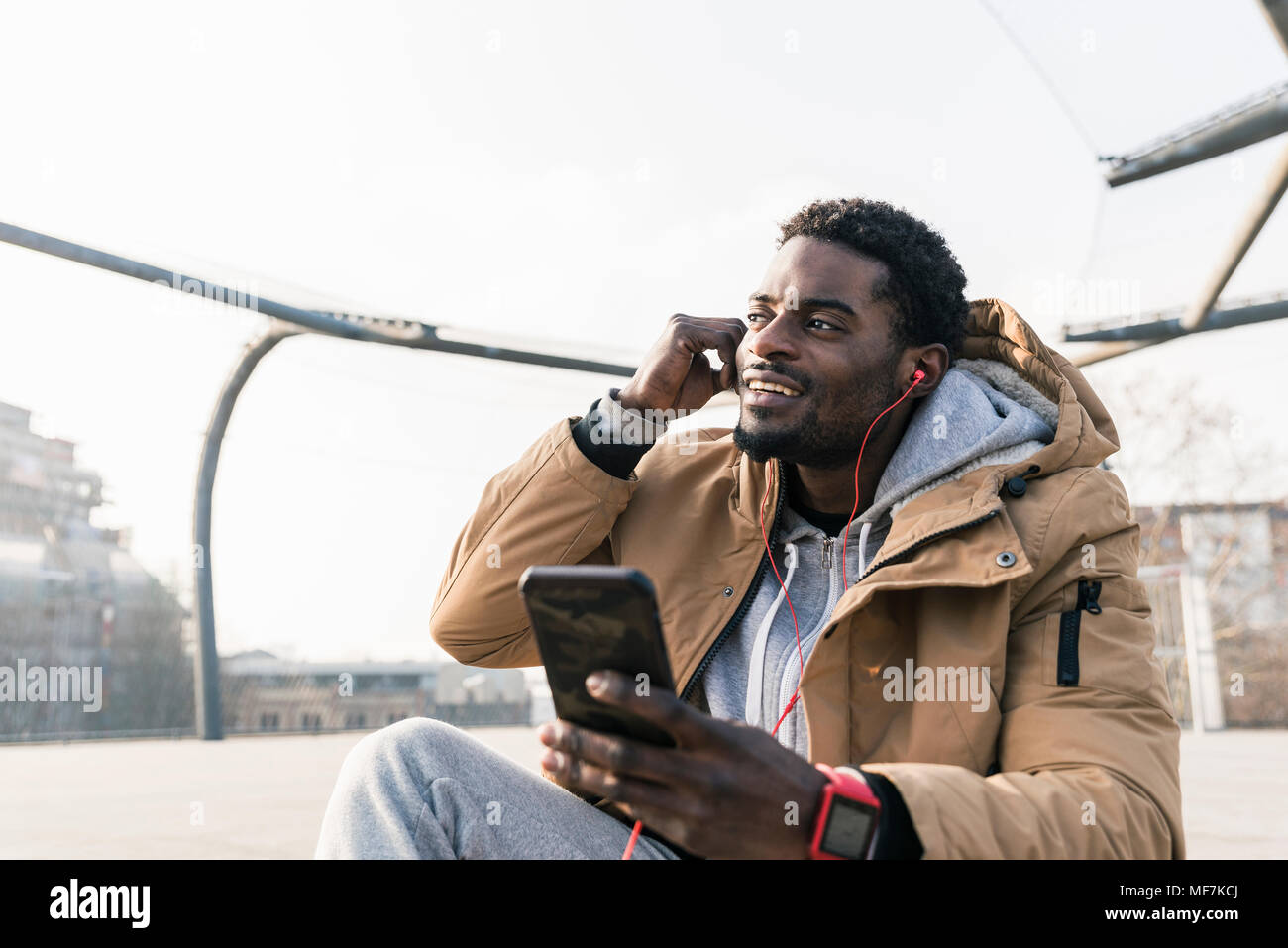 Lächelnden jungen Mann mit Smartphone und Ohrhörer im Freien Stockfoto
