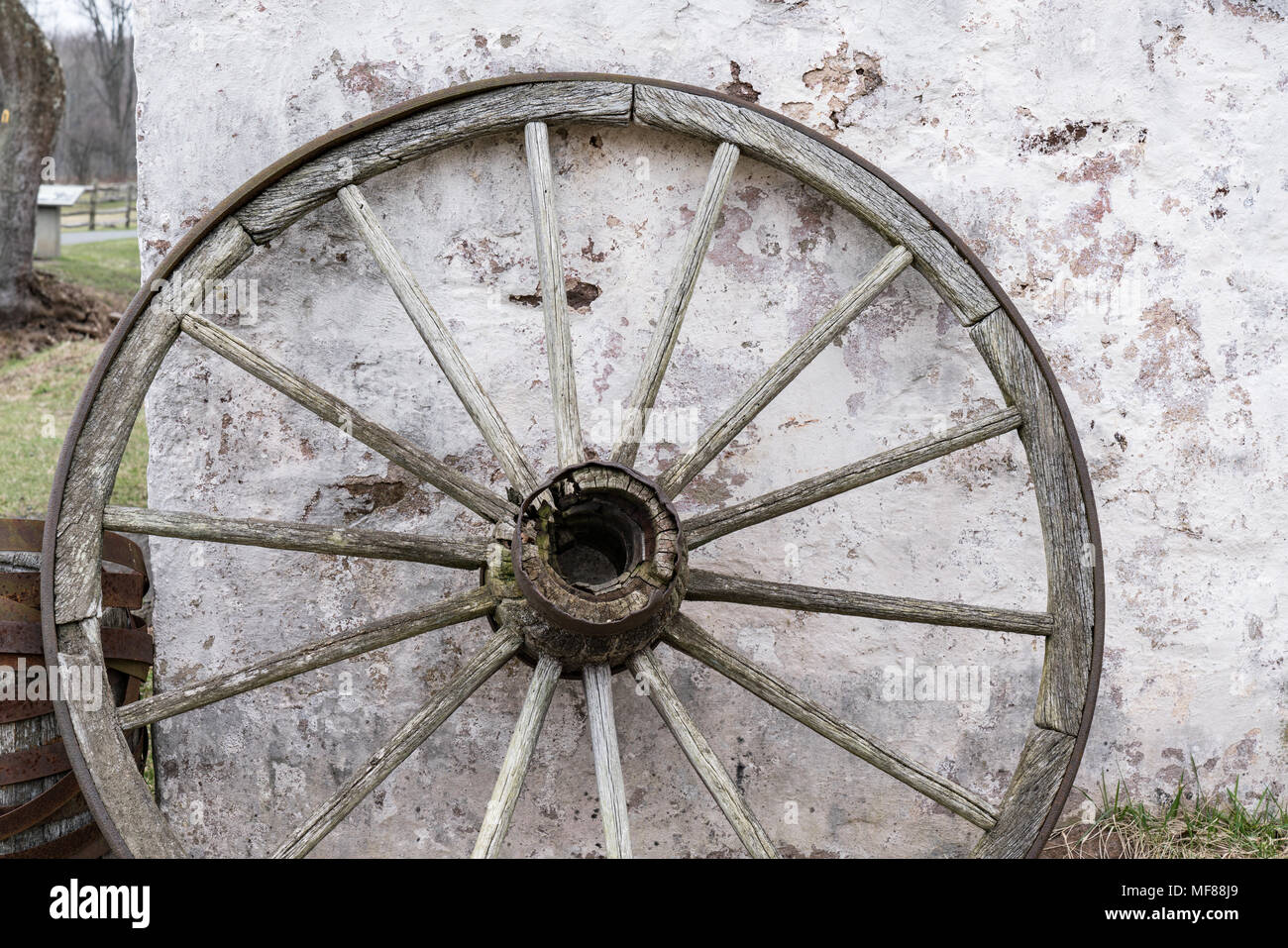 Alten hölzernen Wagen Rad lehnte sich gegen die Mauer aus Stein Stockfoto