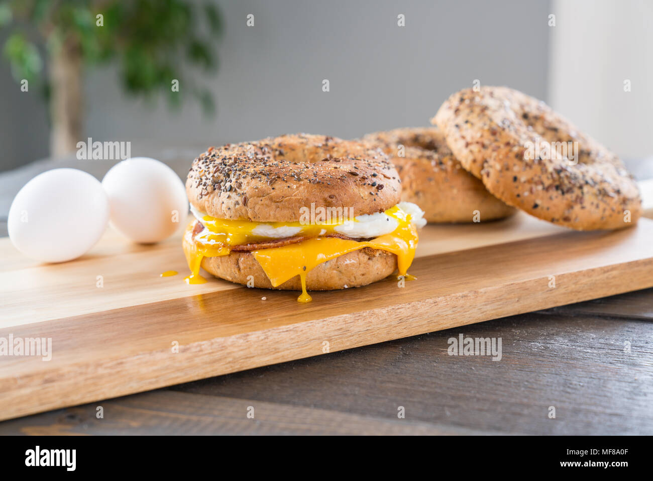 Canadian Bacon, Ei und Käse Breakfast Sandwich mit einem alles Bagel auf Schneidebrett mit Gabel läuft aus Stockfoto