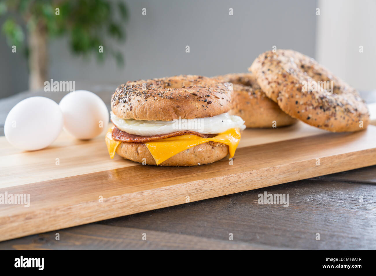 Canadian Bacon, Ei und Käse Breakfast Sandwich mit einem alles Bagel auf Schneidebrett Stockfoto