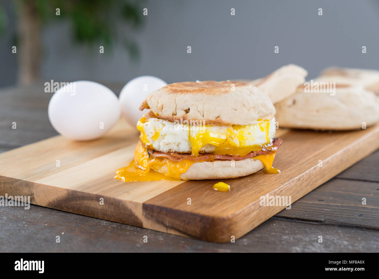 Canadian Bacon, Ei und Käse Breakfast Sandwich mit Englisch muffin auf Schneidebrett mit Gabel Stockfoto