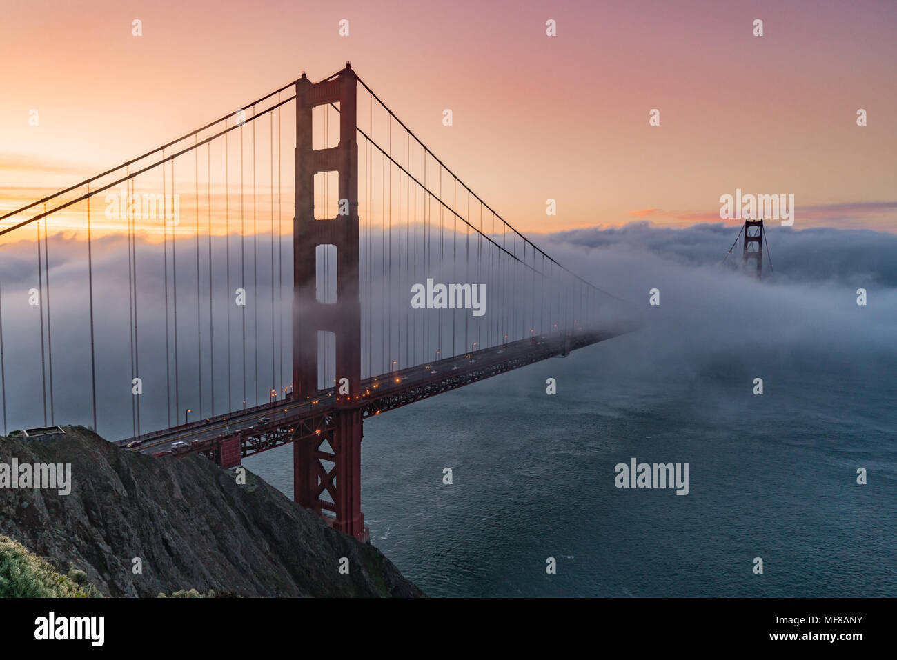 Nebel driftet durch die Bucht von San Francisco über die Golden Gate Bridge bei Sonnenaufgang Stockfoto