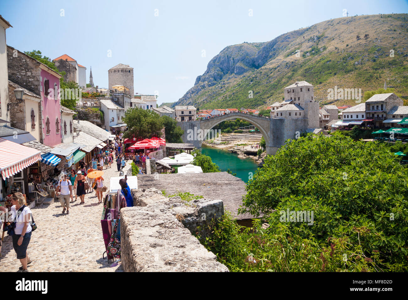Stari Most, der Alten Brücke in Mostar, Bosnien und Herzegowina mit Touristen und Geschäfte im Vordergrund. Stockfoto