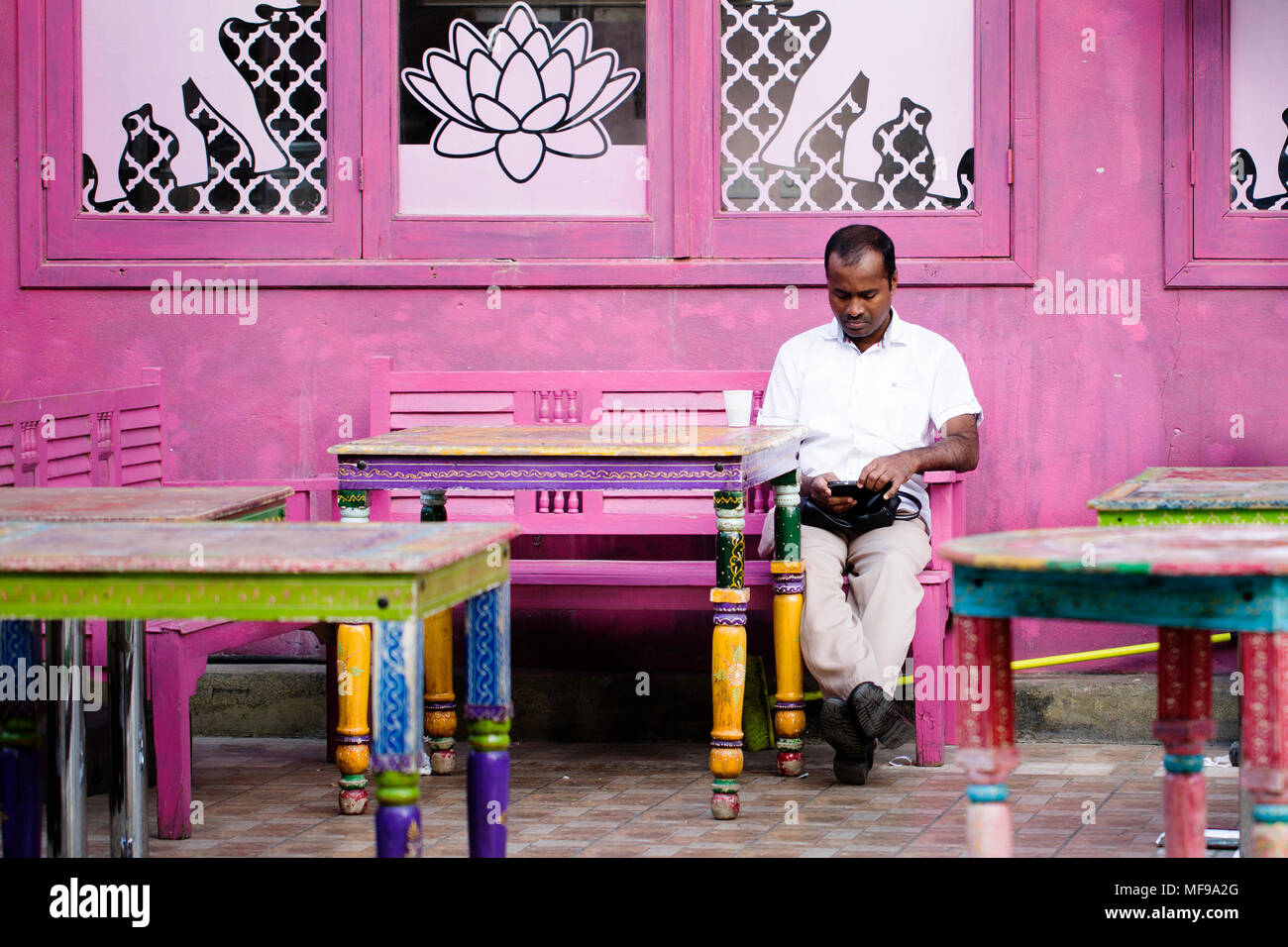 Ein Mann auf seinem Mobiltelefon an ein geschlossenes Restaurant in Souq Mubarakiya, Kuwait Stockfoto