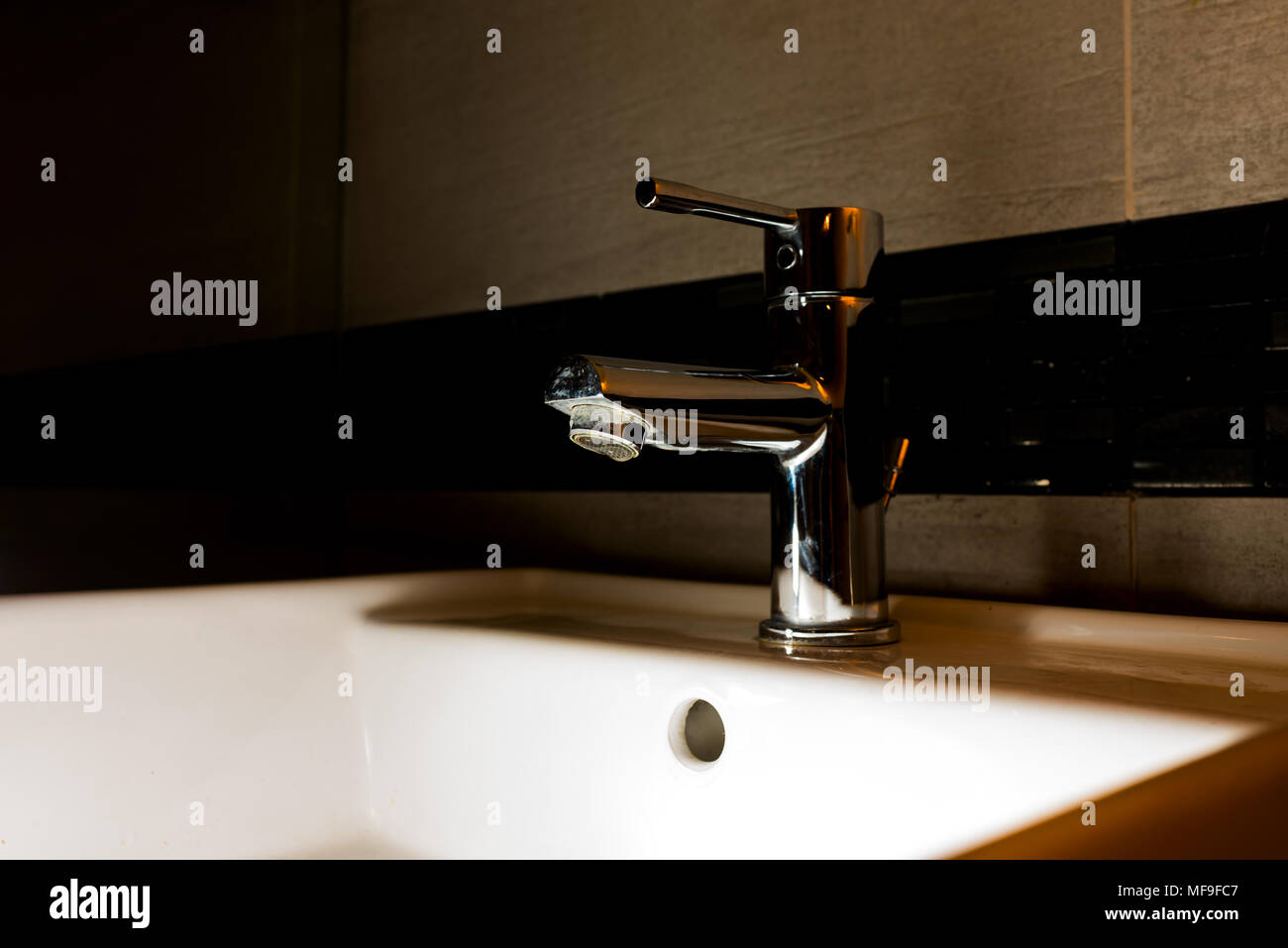 Wasser Schrank in einem dunklen Badezimmer tippen Stockfoto 