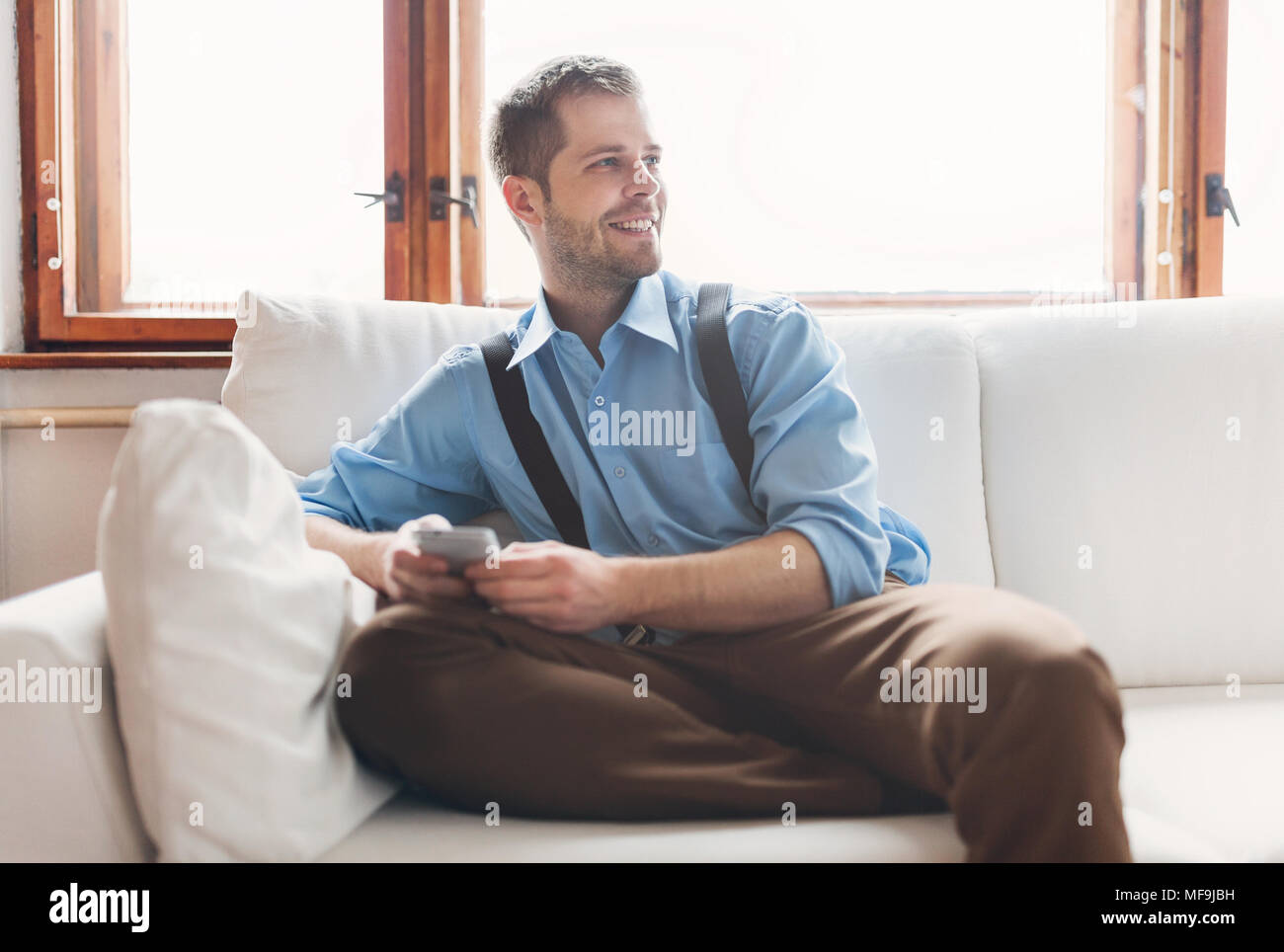 Stattliche Mann sitzt auf einem Sofa und texting von seinem smart phone Stockfoto
