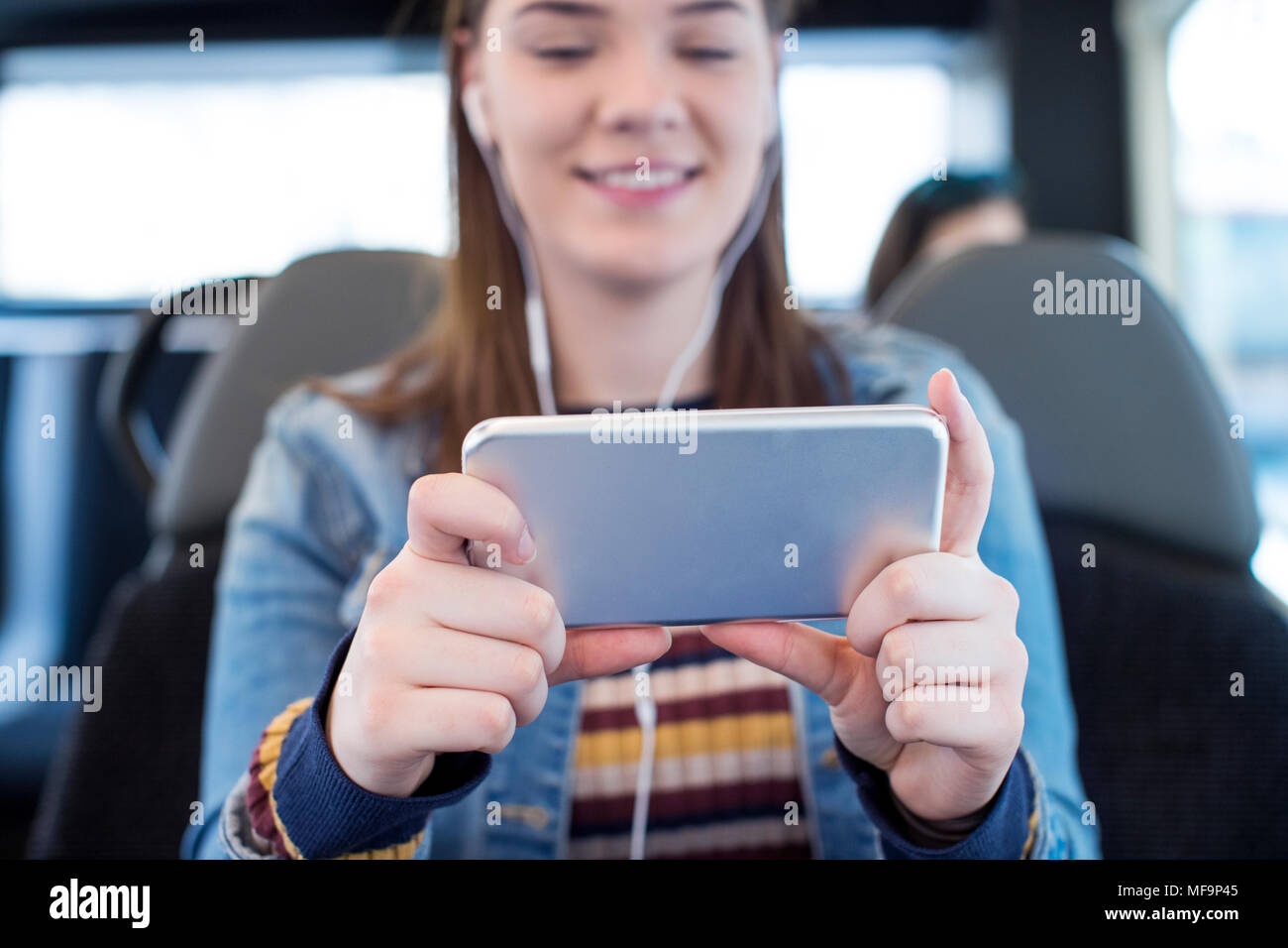 Junge Frau beobachten Film auf Mobiltelefon während der Fahrt zur Arbeit Stockfoto