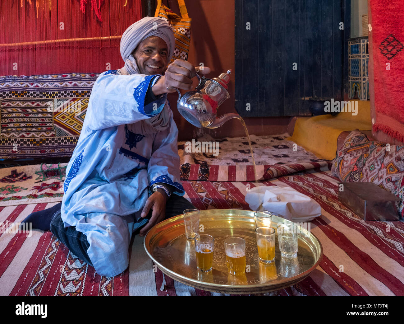 Ein Berber Mann in traditioneller Kleidung gießt Pfefferminztee, Tinghir, Hoher Atlas, Marokko Stockfoto