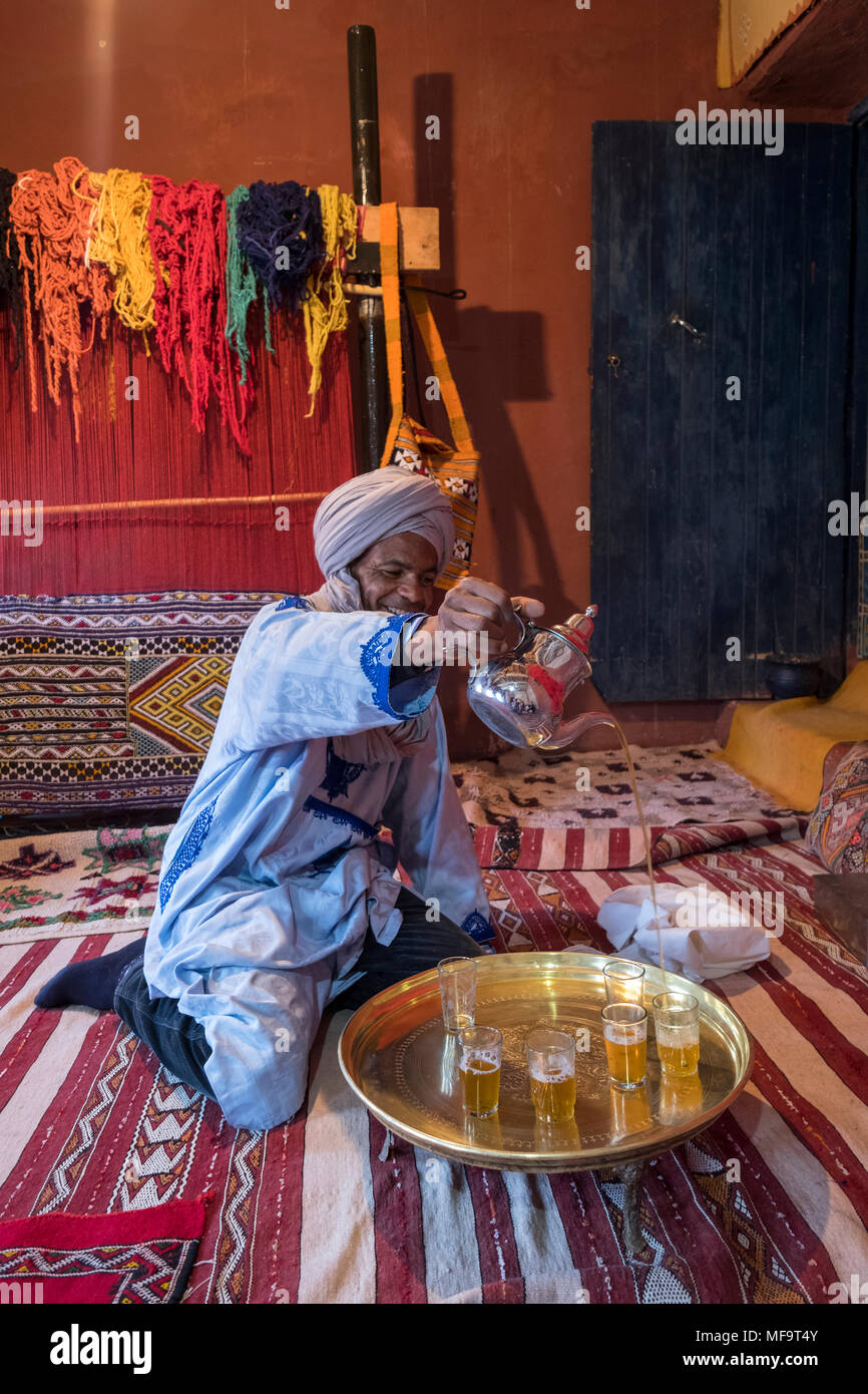 Ein Berber Mann in traditioneller Kleidung gießt Pfefferminztee in seinem Haus, Tinghir, Hoher Atlas, Marokko Stockfoto