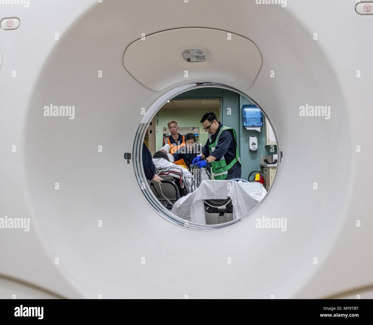 180423-N-RM 689-0116 PAZIFISCHEN OZEAN (23.04.2018) Medizinisches Personal ein mock Patienten in der CT-bringen Zimmer während einer Messe Unfallversicherung bohren an Bord Military Sealift Command Hospital Ship USNS Mercy (T-AH 19), 2018. Barmherzigkeit ist derzeit zur Unterstützung der pazifischen Partnerschaft 2018 (PP18) bereitgestellt werden. PP18's Mission ist es, gemeinsam mit Gastgeber und Partner Nationen zu arbeiten regionaler Interoperabilität und Disaster Response Funktionen, erhöhen die Stabilität und Sicherheit in der Region zu stärken, und neue und dauerhafte Freundschaften in der gesamten indopazifischen Region fördern. Pazifische Partnerschaft, der nun in seinem 13. Iteration ist. Stockfoto