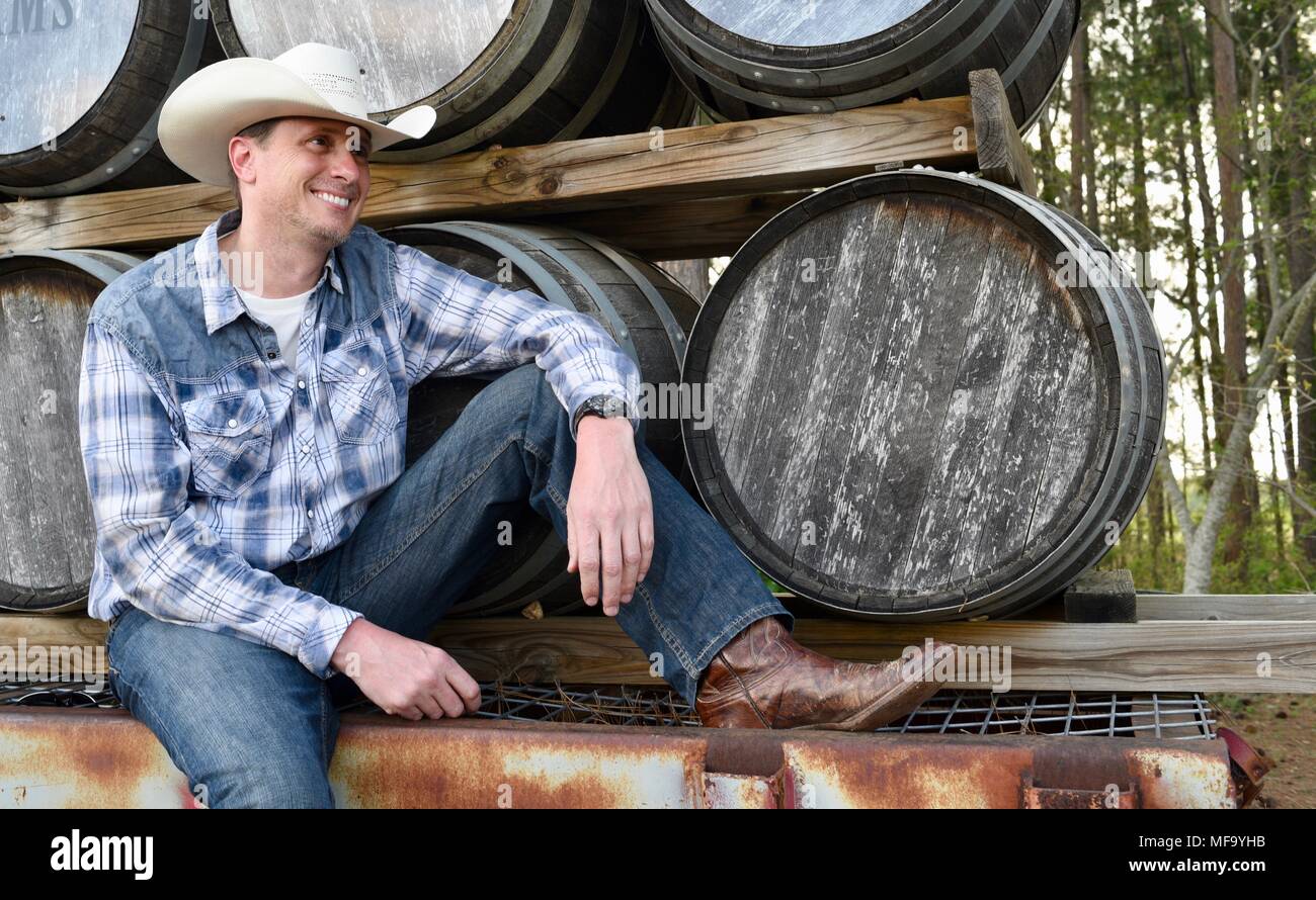 Western Cowboy sitzen auf Tieflader mit Holz Whisky Fässern oder Fässer im Das Peach Haus, Fredericksburg, Texas, USA. Stockfoto