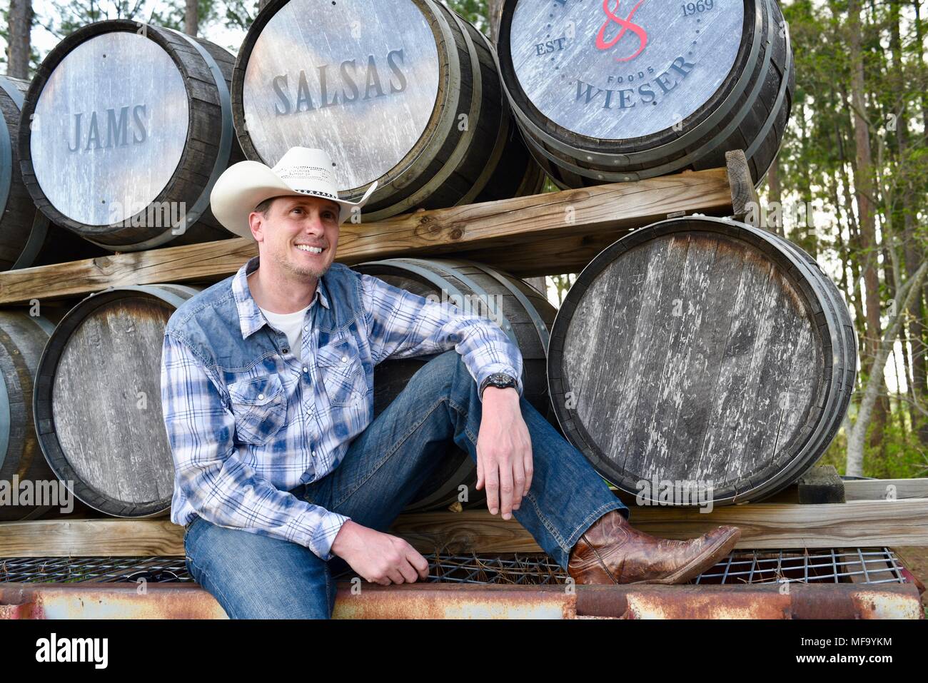 Western Cowboy sitzen auf Tieflader mit Holz Whisky Fässern oder Fässer im Das Peach Haus, Fredericksburg, Texas, USA. Stockfoto