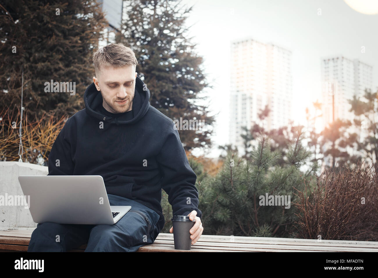 Junger Mann mit Laptop auf den Knien. Schwarz Kaffee Tasse ist neben ihm. Stockfoto
