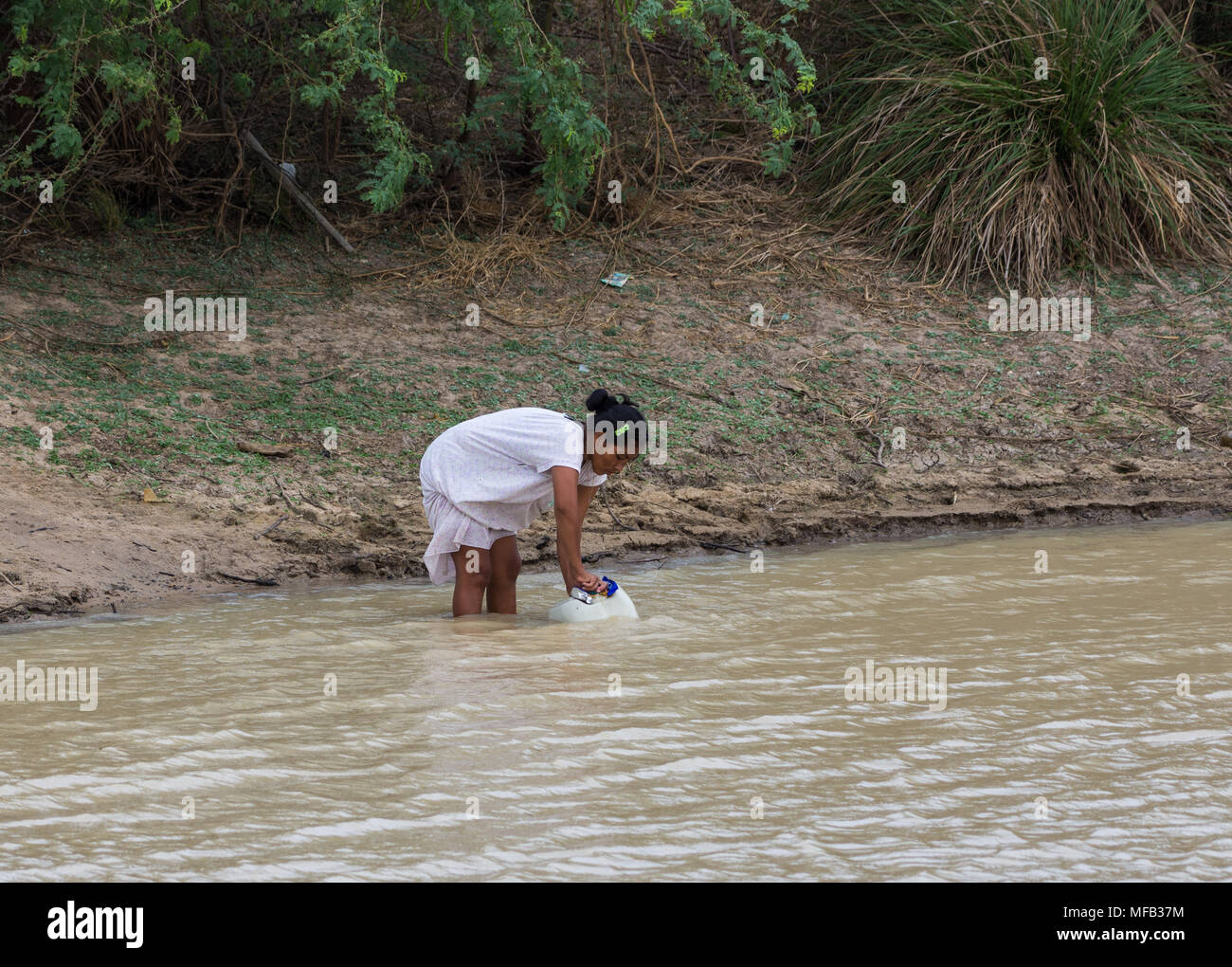 Eine junge Frau füllt einen grossen Krug Wasser in einem Teich im ländlichen Bereich. Kolumbien, Südamerika. Stockfoto