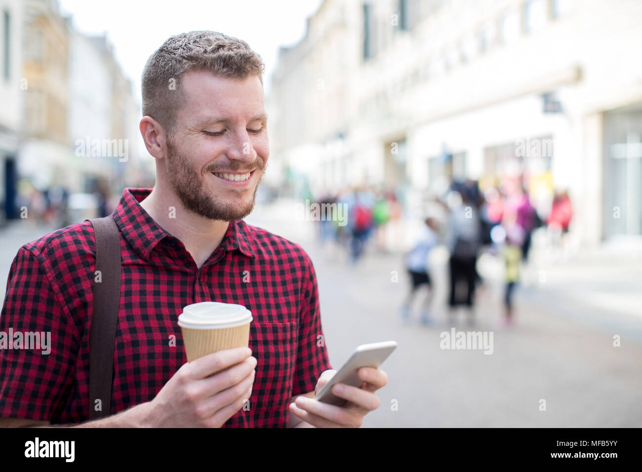 Man Walking entlang der Straße der Stadt lesen SMS auf Handy Stockfoto