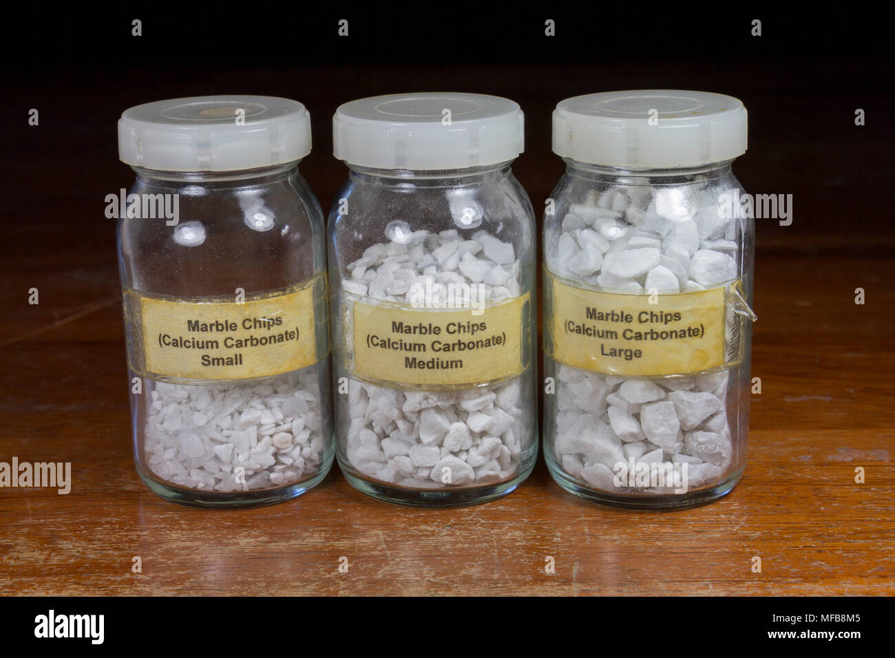 Drei Gläser von Calciumcarbonat (Marmor) Chips variieren von klein, mittelgroß bis groß. Wie in einem britischen Sekundär-/High School verwendet. Stockfoto