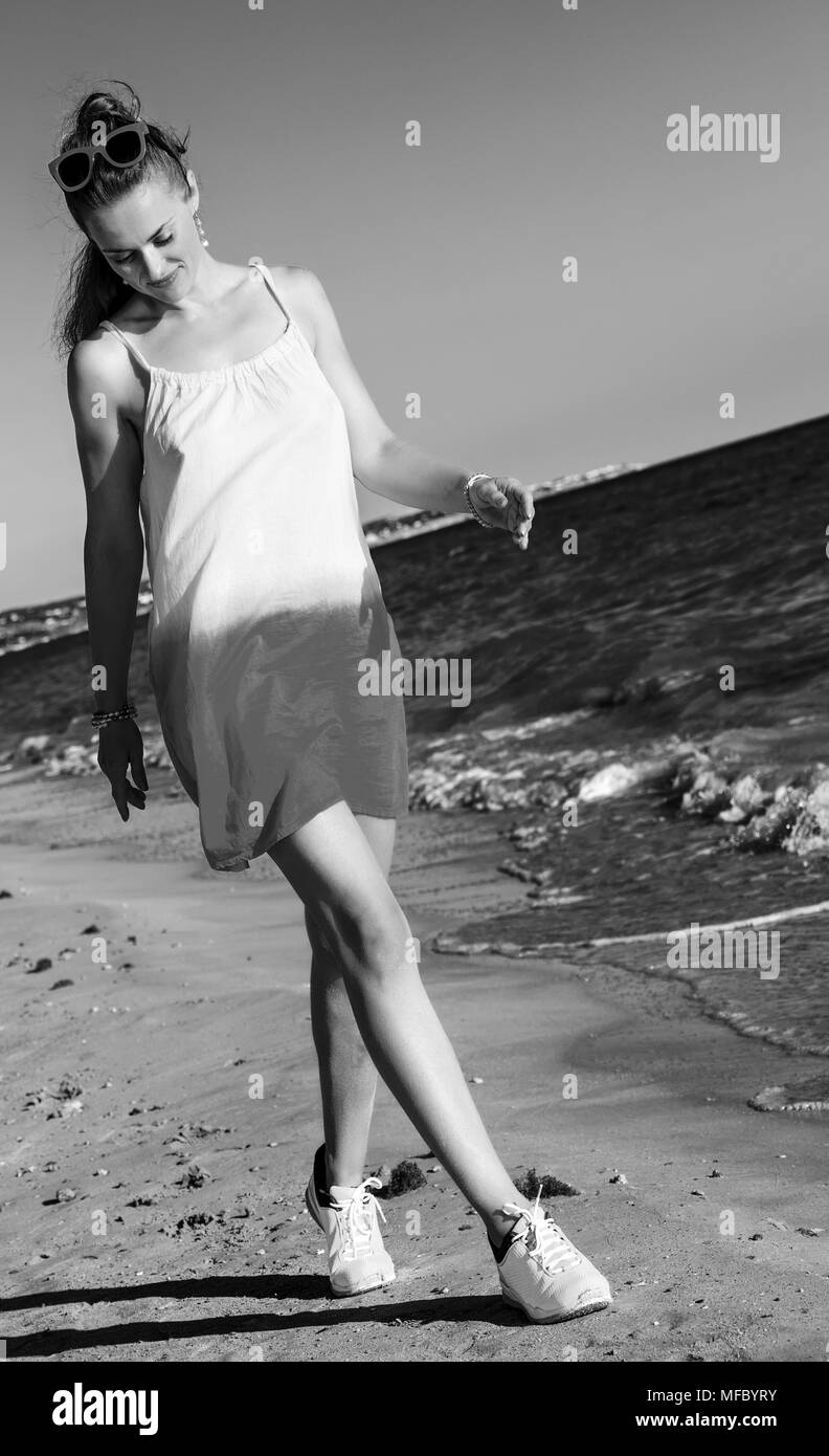 Wunderbar gelaunt. aktive Frau in Kleid auf der Seeküste am Abend zu Fuß Stockfoto