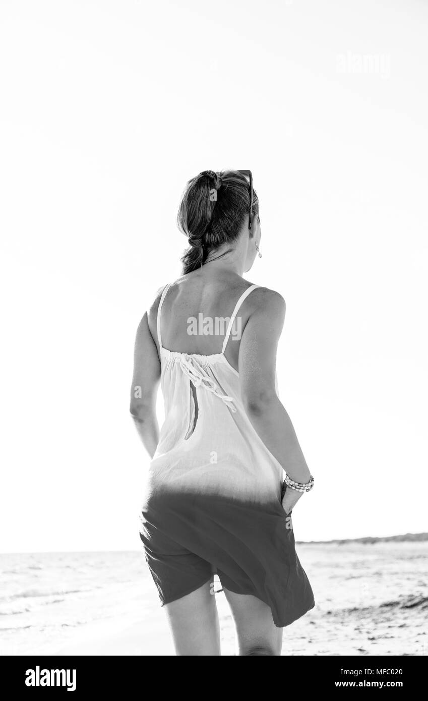 Wunderbar gelaunt. junge Frau im Kleid auf der Seeküste am Abend zu Fuß Stockfoto