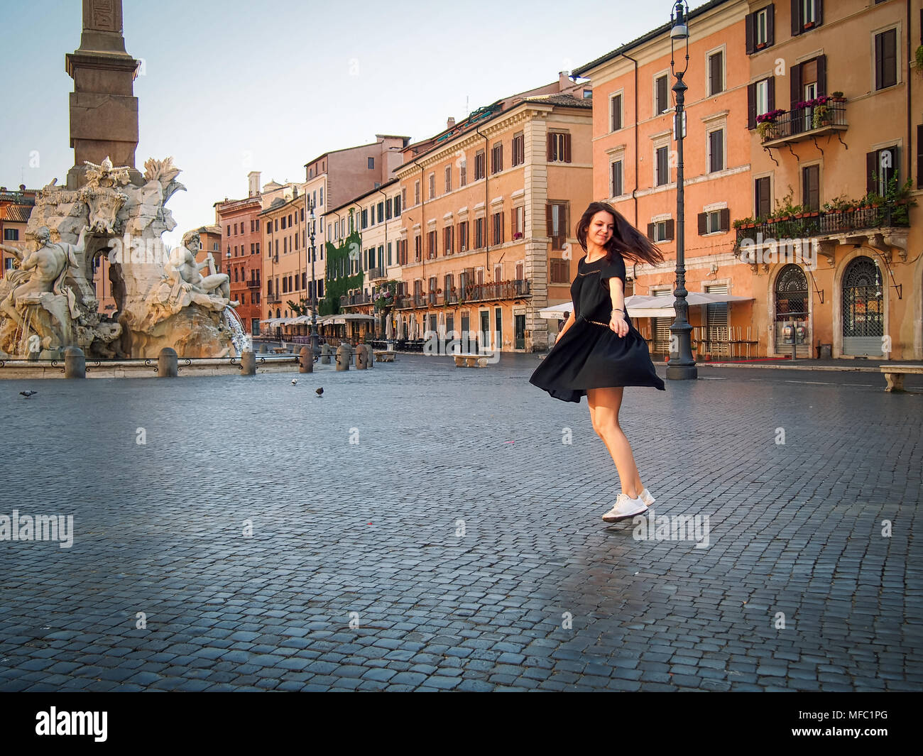 Junge Mädchen tanzen in einem schwarzen Kleid in den Morgen auf der Piazza Navona, Rom, Italien Stockfoto