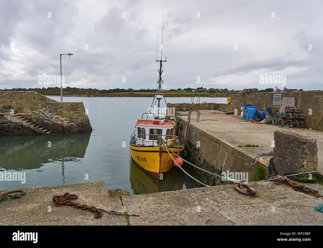 Eine lokale gelb Fischerboot neben der Hafeneinfahrt von Fethard Harbour im County Wexford, südlichen Irland vertäut. Stockfoto