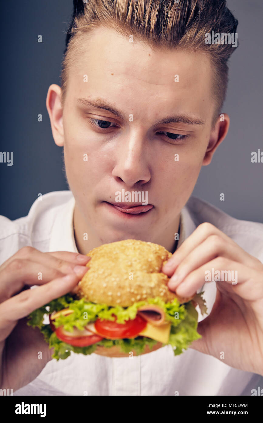 Junger Mann auf der Suche nach einem frischen Burger Stockfoto