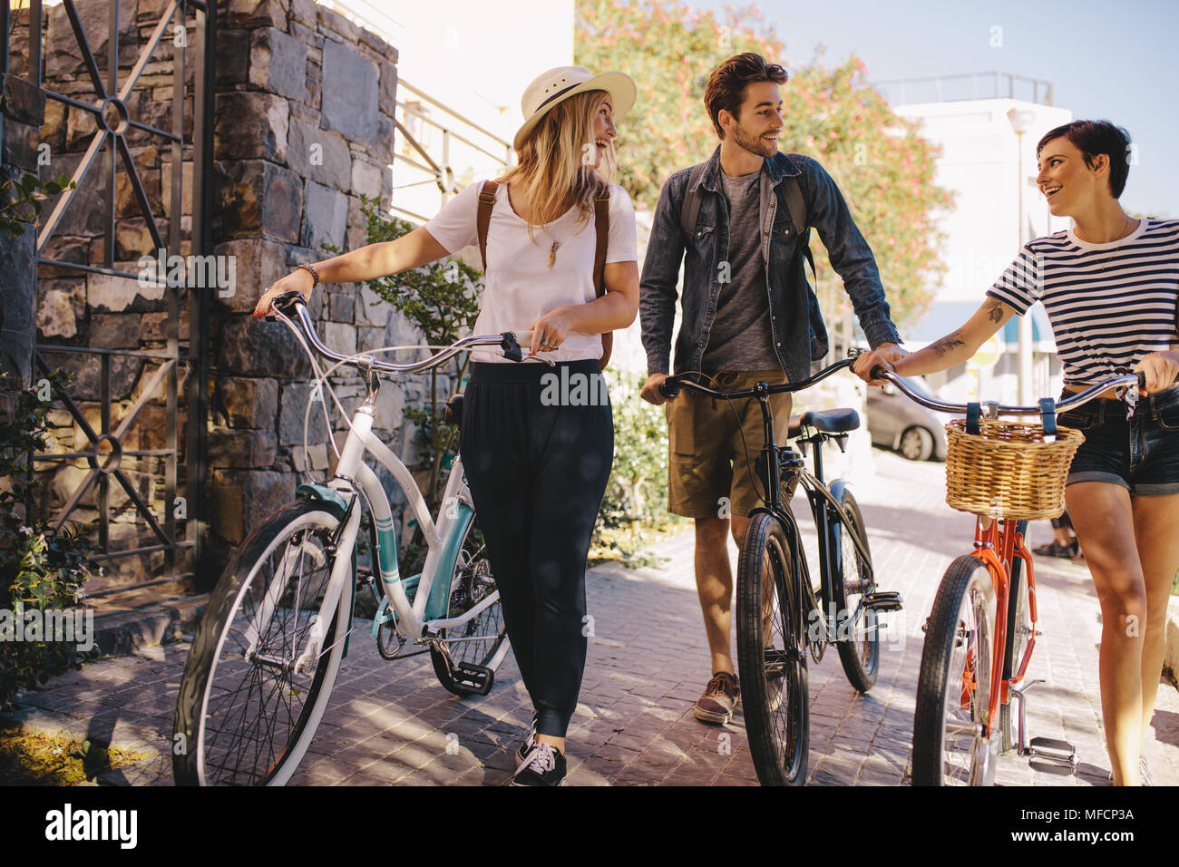 Drei junge Freunde zusammen gehen, Spaß zu haben. Junge Menschen mit Fahrrädern zu Fuß draußen in der Stadt. Stockfoto