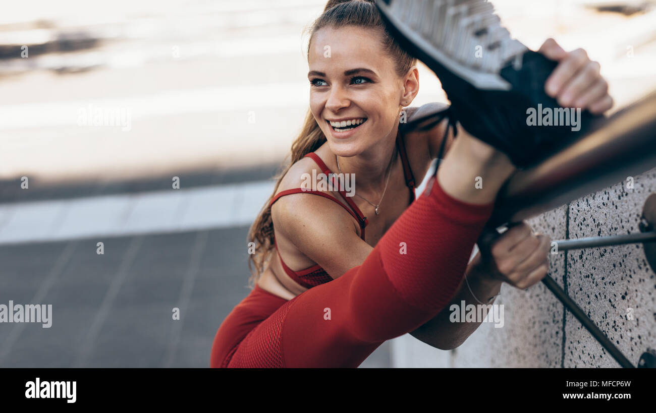 Passen Sportlerin, Bein, erstreckt sich auf ein Geländer. Weibliche Athleten warm up erstreckt sich im Freien zu tun. Stockfoto