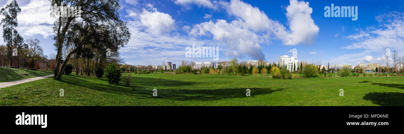 Panorama der großen, leeren grünen Rasen Rasenfläche und Blick auf die Stadt. Parque da Devesa städtischen Park. Blauer Himmel, weiße Wolken. Vila Nova de Famalicao, Portugal Stockfoto