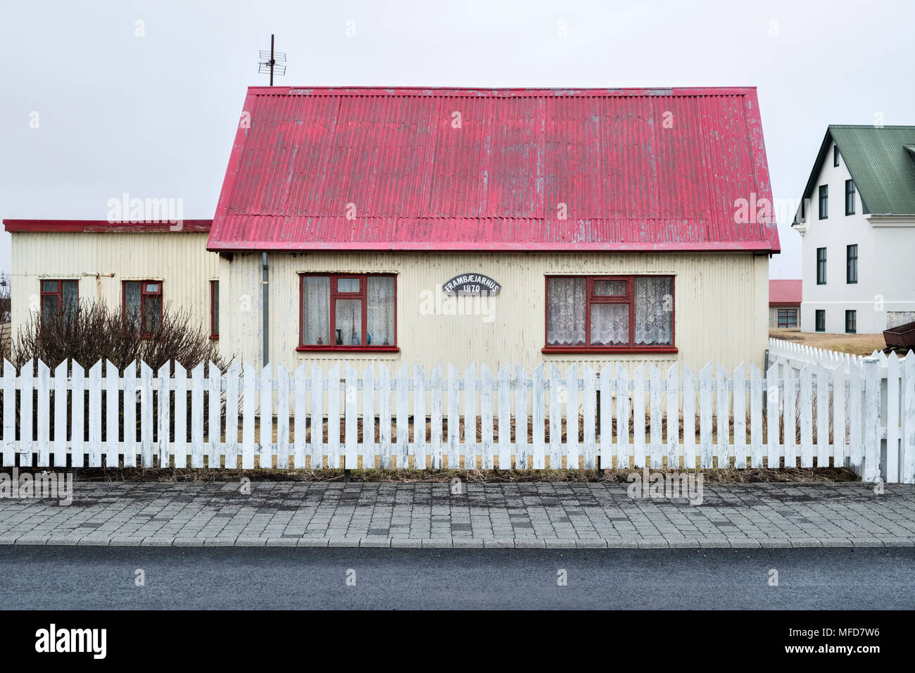 Eyrarbakki, South Island. Typische alte 19c Wellpappe - Eisen Cottage mit weissen Lattenzaun, mit einem Schild es dating bis 1870 Stockfoto