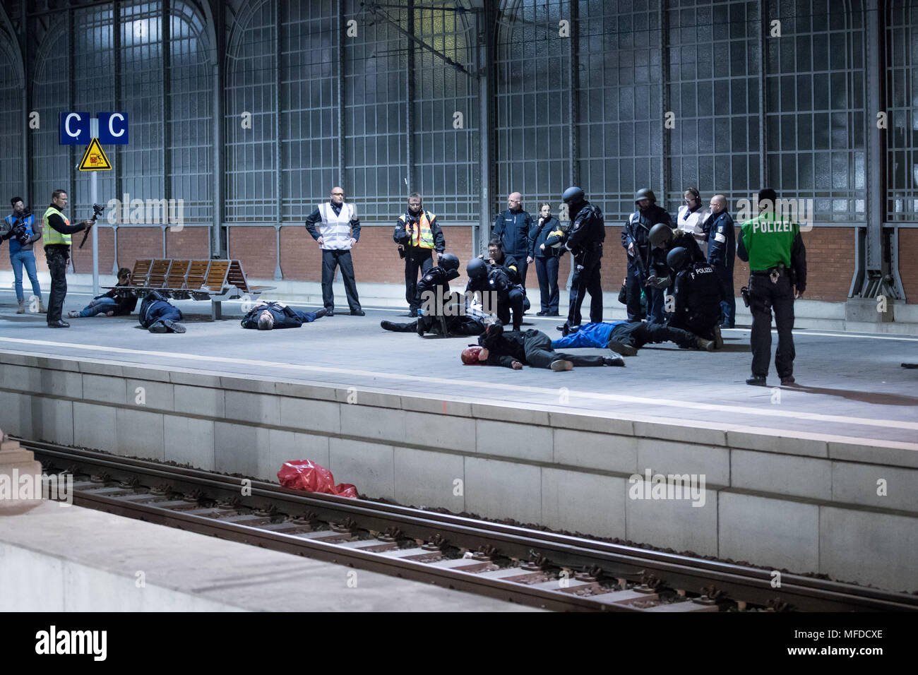 24 April 2018, Deutschland, Lübeck: Polizisten und Passanten über eine Plattform laufen während einer Demonstration für eine Anti-Terror-Übung in Lübeck entfernt. Fast 700 Polizisten von Staat und Land sowie über 120 Einsatzkräfte der Feuerwehr und Notfalldienste beteiligen sich an dieser Übung am Hauptbahnhof. Foto: Christian Charisius/dpa Stockfoto