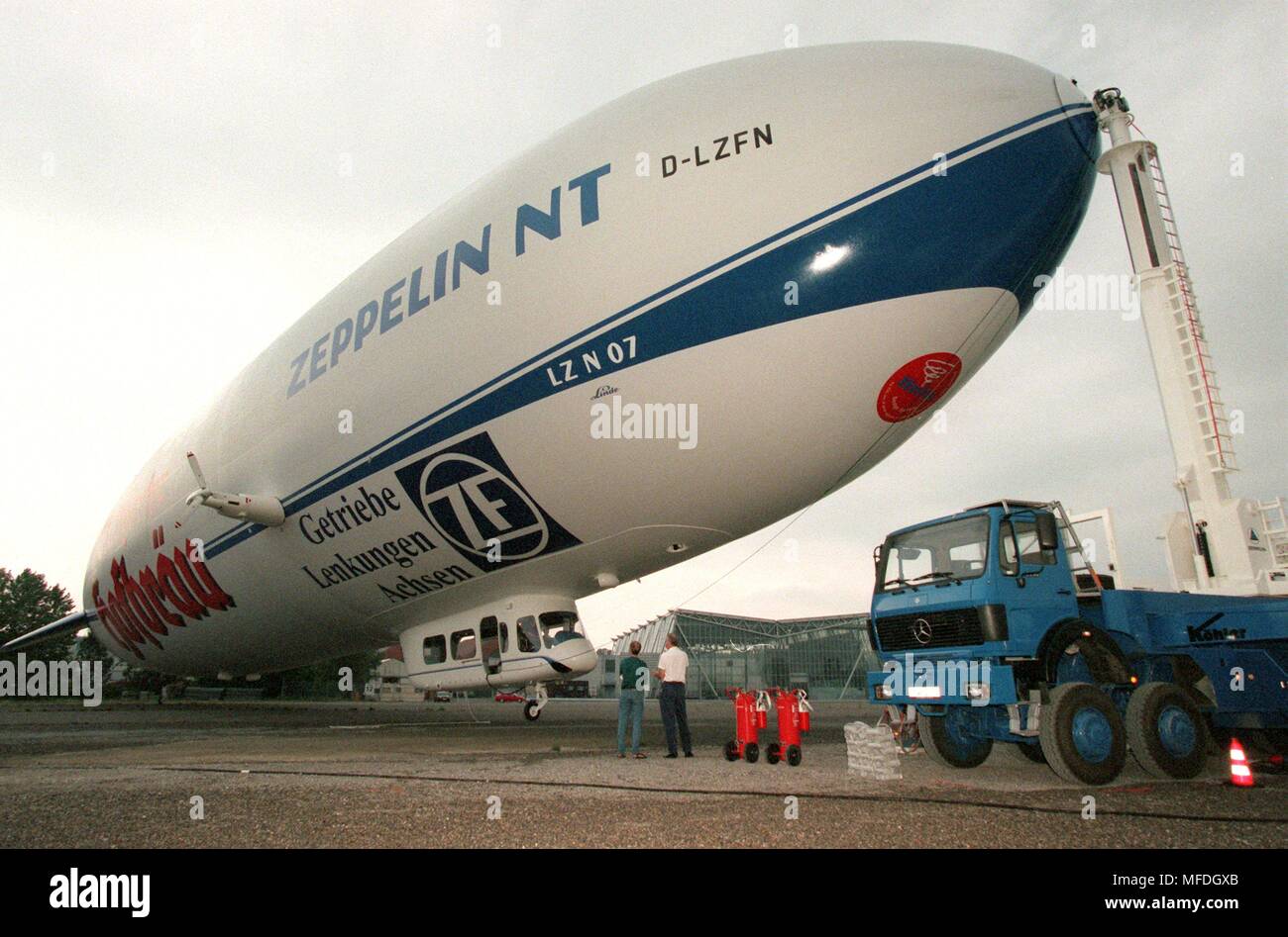 "Roll-out" der neue Zeppelin in Friedrichshafen: Nachdem es aus dem Hangar gezogen wurde und befestigt, um einen Anker Mast, der 75 Meter langen Zeppelin NT (Neue Technologie) schwimmt auf 8.8.1997 auf dem Gelände der Messe in Friedrichshafen. Der erste Flug der High-tech-Zeppelin ist für Ende August und Mitte September geplant. Passagiere - maximal zwölf - erwartet, eine Fahrt mit dem Luftschiff im Sommer 1988 zu genießen. 7200 Kubikmeter aus nicht brennbarem Helium füllen die Hüllkurve des 'Silver Zigarre". Drehbare Propeller machen das NT besonders wendig und dawith sicher. | Verwendung weltweit Stockfoto