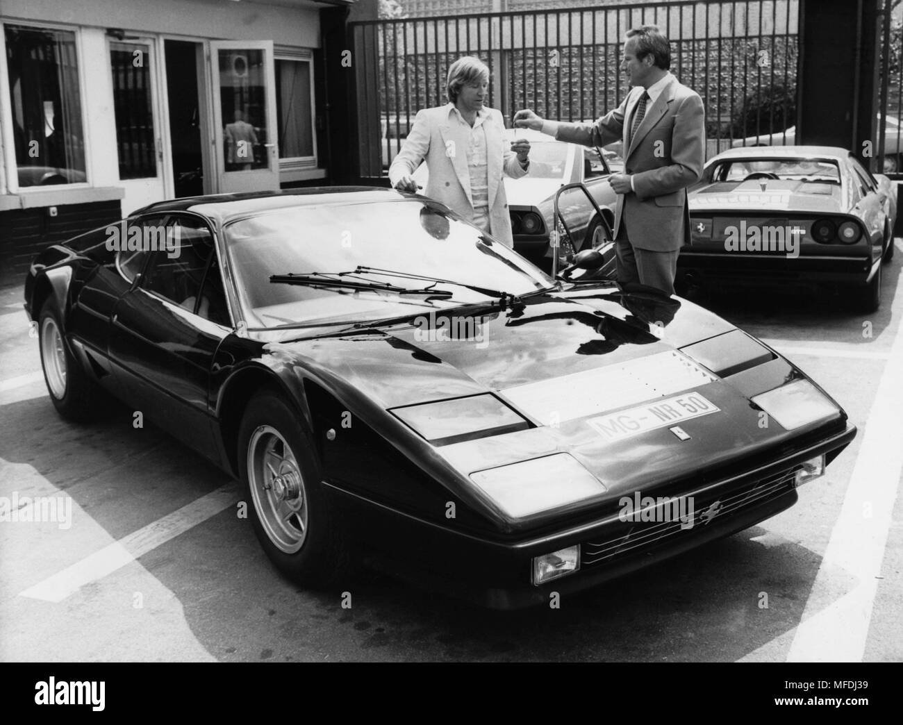 Ex-Fußball-Star Günter Netzer (l) stimmt auch nach dem Ende seiner aktiven Karriere, der Kassierer: die pechschwarze Ferrari 512 Berlinetta Boxer, die Helmut Becker (r) aus der Deutschen Ferrari exklusiver Importeur Auto-Becker in Düsseldorf am 20. Juli 1977 aufgegeben, mit Kosten von mindestens 107 000 Mark. | Verwendung weltweit Stockfoto