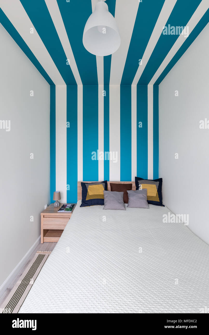 Einfache Schlafzimmer mit dekorativen blauen und weißen Streifen an der Wand Stockfoto